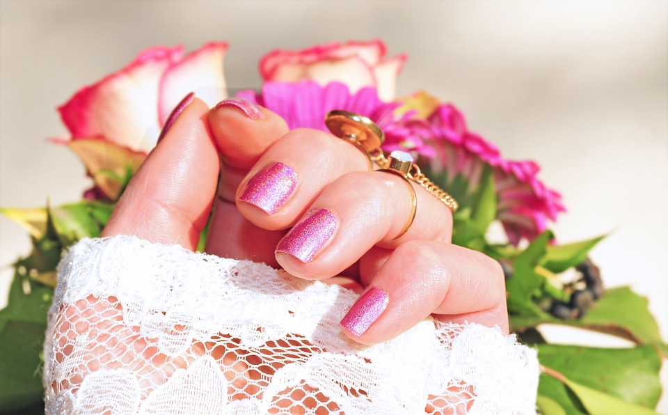 Фотография розовых ногтей на фоне цветов.